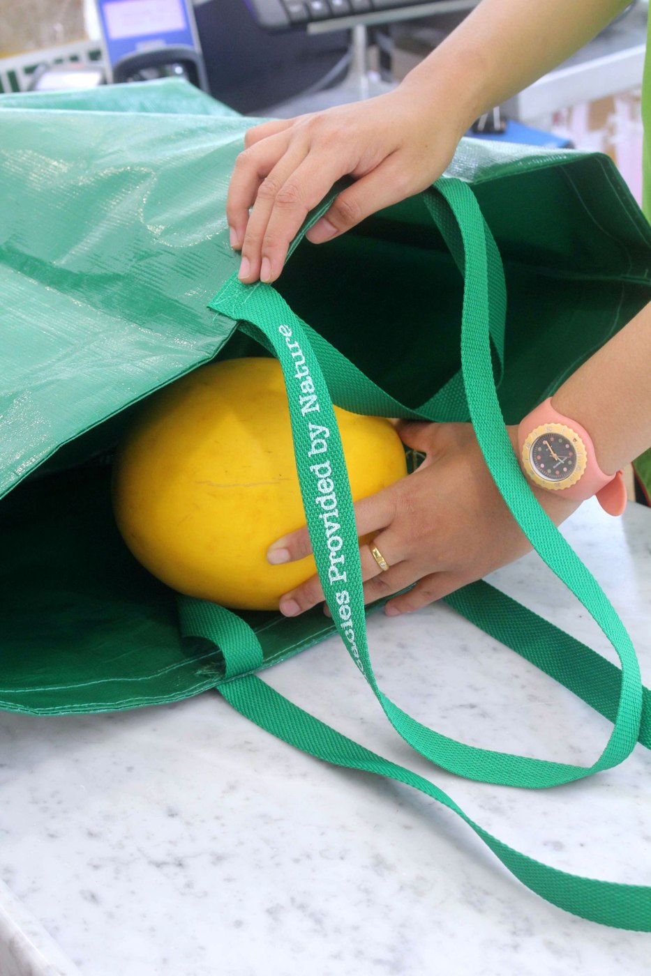 Woman packing melon into reusable shopping bag