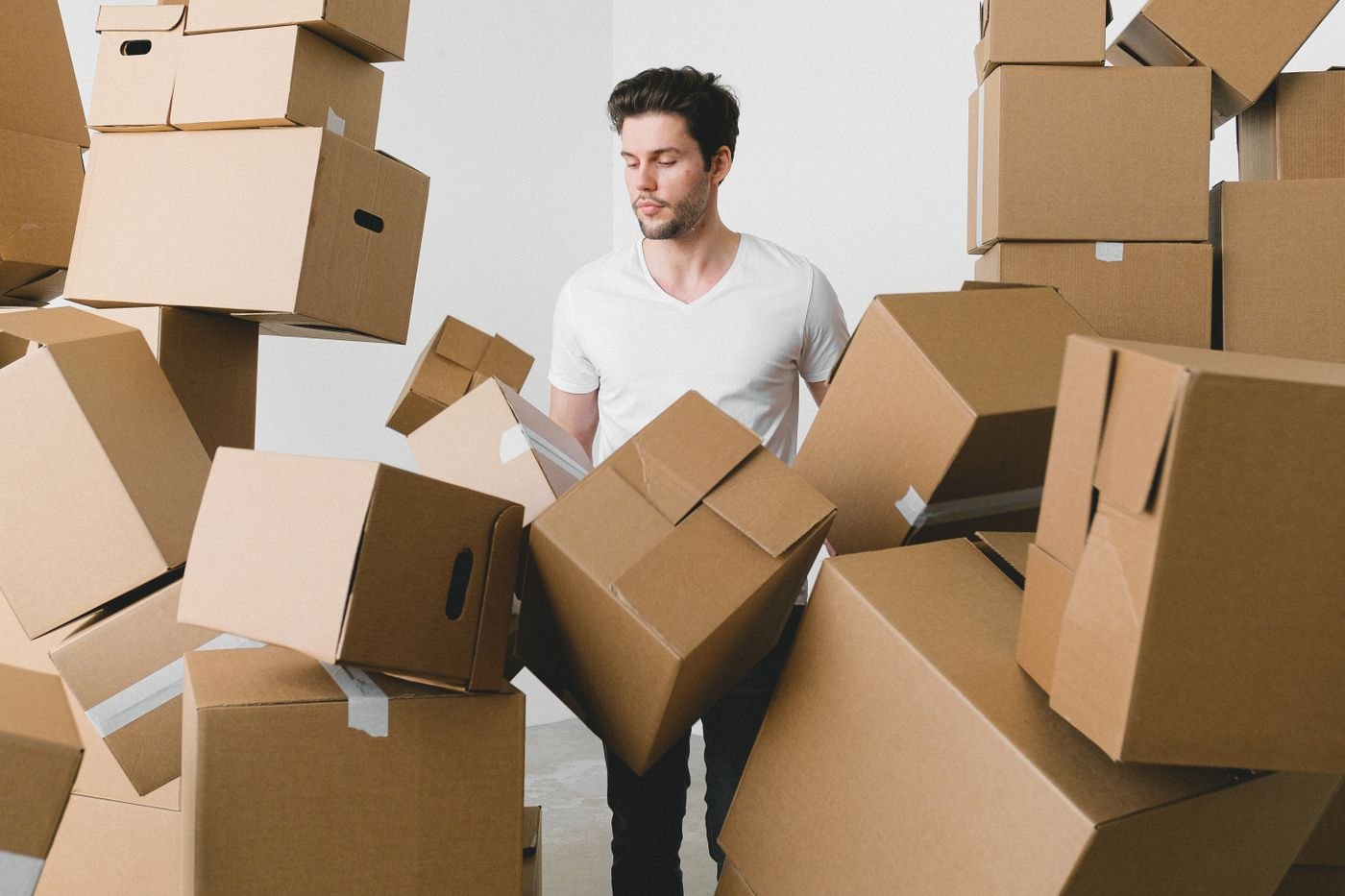 Man between stacks of cardboard boxes at home
